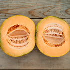 Two halves of an Amish melon with vibrant orange flesh and seeds, resting on a rustic wooden surface.