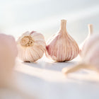 Chesnok Red garlic bulbs with purple-striped papery skins arranged on a bright, sunlit surface.