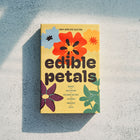 Yellow matchbox-style Edible Petals seed kit featuring colorful flower illustrations and a list of included plant varieties.