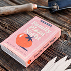 Pink Family Pizza Night seed collection box with tomato illustration on a rustic wooden surface with garden markers.