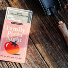 Family Pizza Night seed kit box with Italian Genovese Basil packet on a rustic wooden surface next to a garden trowel.