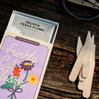 Freshly Cut Blooms seed kit in a purple box with birch garden markers on a wooden surface.