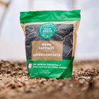 Gaia Green Worm Castings bag standing upright in soil, featuring green and brown packaging with a circular logo.