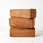 Three rectangular Coco Coir Bricks stacked vertically on a white wooden surface.