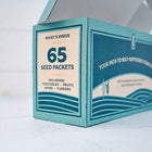 Teal cardboard box for Emergency Heirloom Seed Bank containing 65 packets of vegetables, fruits, herbs, and flowers.