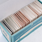Open teal storage box filled with rows of labeled paper seed packets.