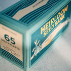 Teal cardboard box for an Emergency Heirloom Seed Bank containing 65 packets of vegetables, herbs, and flowers.
