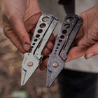 Two Herb Harvest and Strip Tools in stainless steel and dark metal held in hands, featuring copper accents and finger holes.