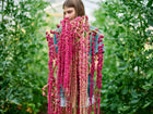 Person holding long, trailing tassels of deep crimson Love-Lies-Bleeding amaranth flowers in a garden.