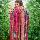 Person holding long, trailing tassels of deep crimson Love-Lies-Bleeding amaranth flowers in a garden.