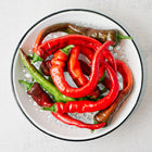 Freshly harvested Hot Portugal peppers in red and green shades inside a white colander.
