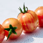 Row of Pink Bumble Bee cherry tomatoes with rosy pink skin and golden stripes, covered in small water droplets.
