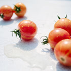 Freshly picked Pink Bumble Bee cherry tomatoes with rosy pink skin and golden stripes on a white surface.