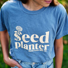 Blue garment-dyed short sleeve Seed Planter t-shirt with a white flower graphic and text on the chest.