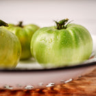 Freshly harvested Aunt Ruby's German Green tomatoes with chartreuse skin in a white enamel colander.