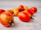 Freshly harvested San Marzano tomatoes with elongated red shapes scattered on a light textured surface.