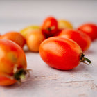Freshly harvested San Marzano tomatoes with elongated red shapes scattered on a light textured surface.