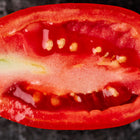 A cross-section of a bright red, plum-shaped Italian Roma tomato showing its meaty flesh and small seeds.