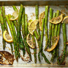 Roasted Mary Washington asparagus spears seasoned with lemon slices on a metal baking sheet.