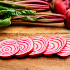 Sliced Chioggia beets showing pink and white candy-striped rings on a wooden cutting board with whole beets in the background.