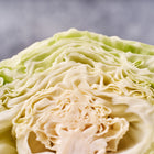Close-up of a halved Early Jersey Wakefield cabbage showing its pale green, tightly layered leaves and cone-shaped structure.