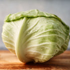 Late Flat Dutch cabbage head with pale green leaves and water droplets on a wooden cutting board.