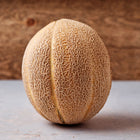 Delicious 51 cantaloupe with heavy netting on a light surface against a rustic wooden background.
