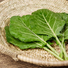 Fresh Morris Heading collard leaves with blue-green, savoyed texture in a woven straw basket.