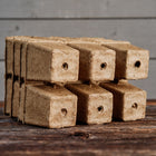 Set of four 3-inch six-cell CowPots made of brown composted manure with drainage holes on a wooden surface.