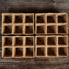 Four brown, biodegradable 3-inch six-cell CowPots arranged on a rustic wooden surface.