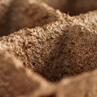 Close-up of a brown, textured 3-inch six-cell CowPot made from composted cow manure.