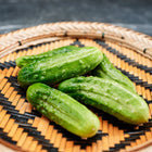 Freshly harvested National Pickling cucumbers arranged on a woven bamboo tray.