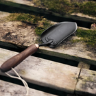 Barebones Garden Trowel with a dark stainless steel blade and wooden handle resting on mossy wooden planks.