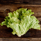 Fresh head of Iceberg lettuce with pale green, ruffled leaves resting on a rustic dark wooden surface.