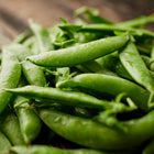 Freshly harvested Sugar Daddy snap peas with plump, glossy green pods piled on a rustic wooden surface.