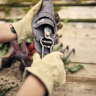 Hands in work gloves sliding a steel Garden Pruner w/ Sheath into its waxed canvas storage pouch.