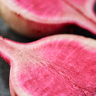 Close-up of halved Watermelon radish showing a vibrant rose-pink interior and pale green skin.