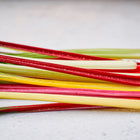 Rainbow Mix Swiss chard stems in vibrant shades of red, yellow, and white with glossy green leaves on a light surface.