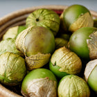 Purple de Milpa tomatillos with papery husks in a woven basket.
