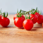 Clusters of bright red Matt's Wild Cherry tomatoes resting on a wooden surface.