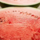 Close-up of two halves of a Crimson Sweet watermelon showing crisp, bright red flesh and dark seeds.