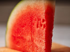 A thick, juicy wedge of bright red Sugar Baby watermelon with a thin green rind.