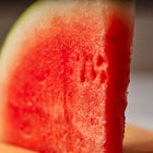 A thick, juicy wedge of bright red Sugar Baby watermelon with a thin green rind.