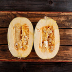 Two halves of a pale yellow Spaghetti squash with visible seeds resting on a rustic wooden crate.