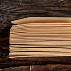 Stack of 24 light-colored 4-inch wooden seed starting labels made from birch veneer on a dark rustic wood surface.