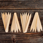 Twenty-four 6-inch wooden seed starting labels made of light birch veneer arranged in four clusters on a dark wood surface.