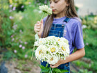 A young girl holding a bouquet of creamy white Polar Bear zinnia flowers in a garden.